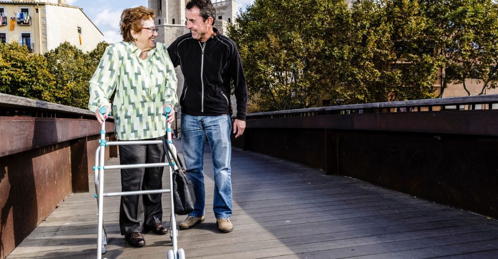 Older lady with a walker being helped by a man