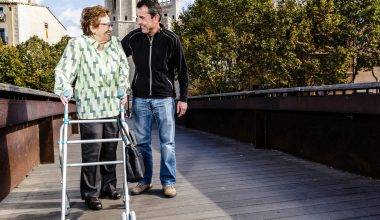 Older lady with a walker being helped by a man
