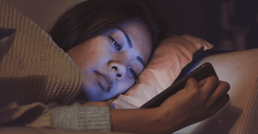 Girl looking at her phone in bed at night time