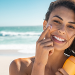 Happy woman applying face sunscreens