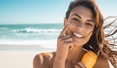 Happy woman applying face sunscreens