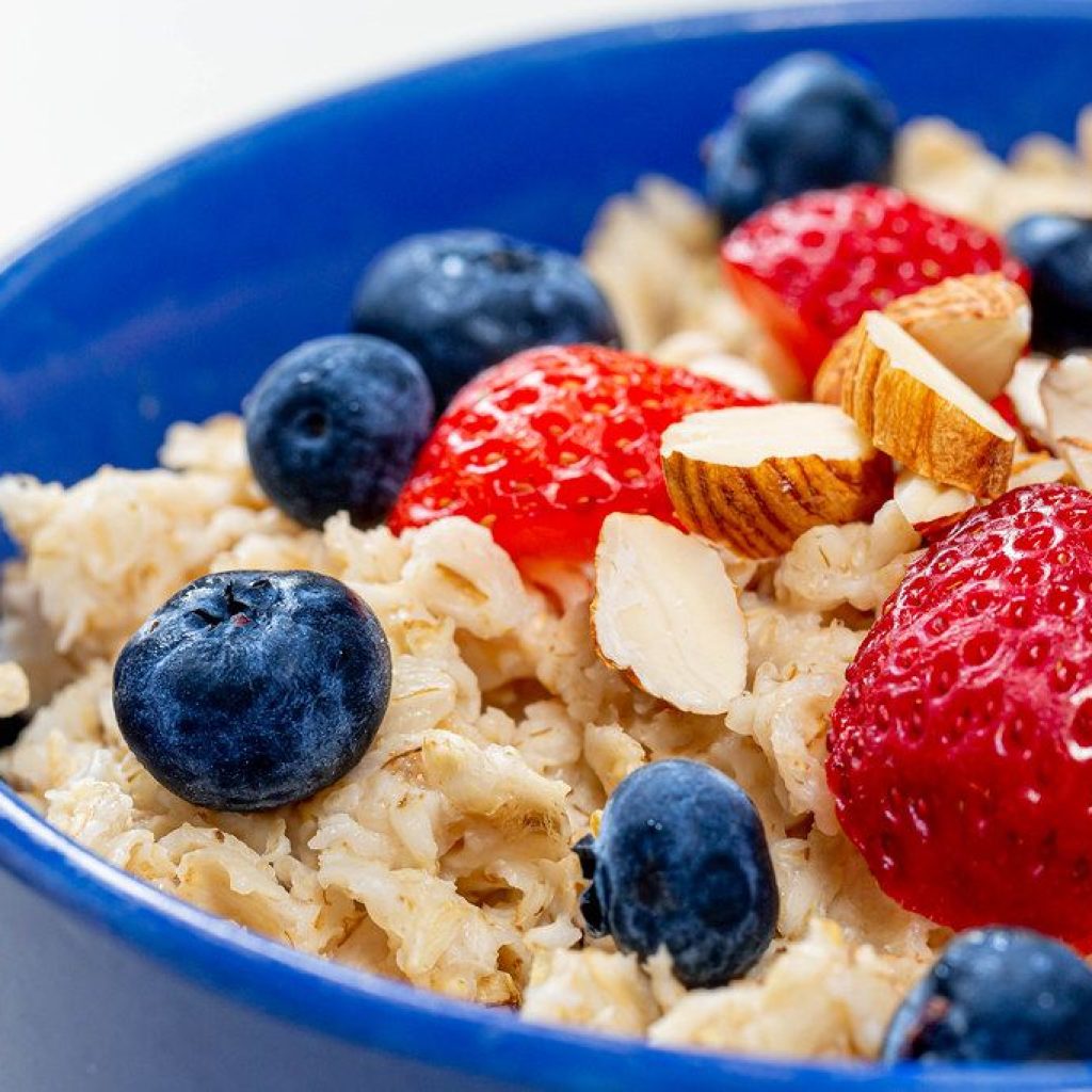 A bowl of oatmeal with strawberries, blueberries, and almonds.