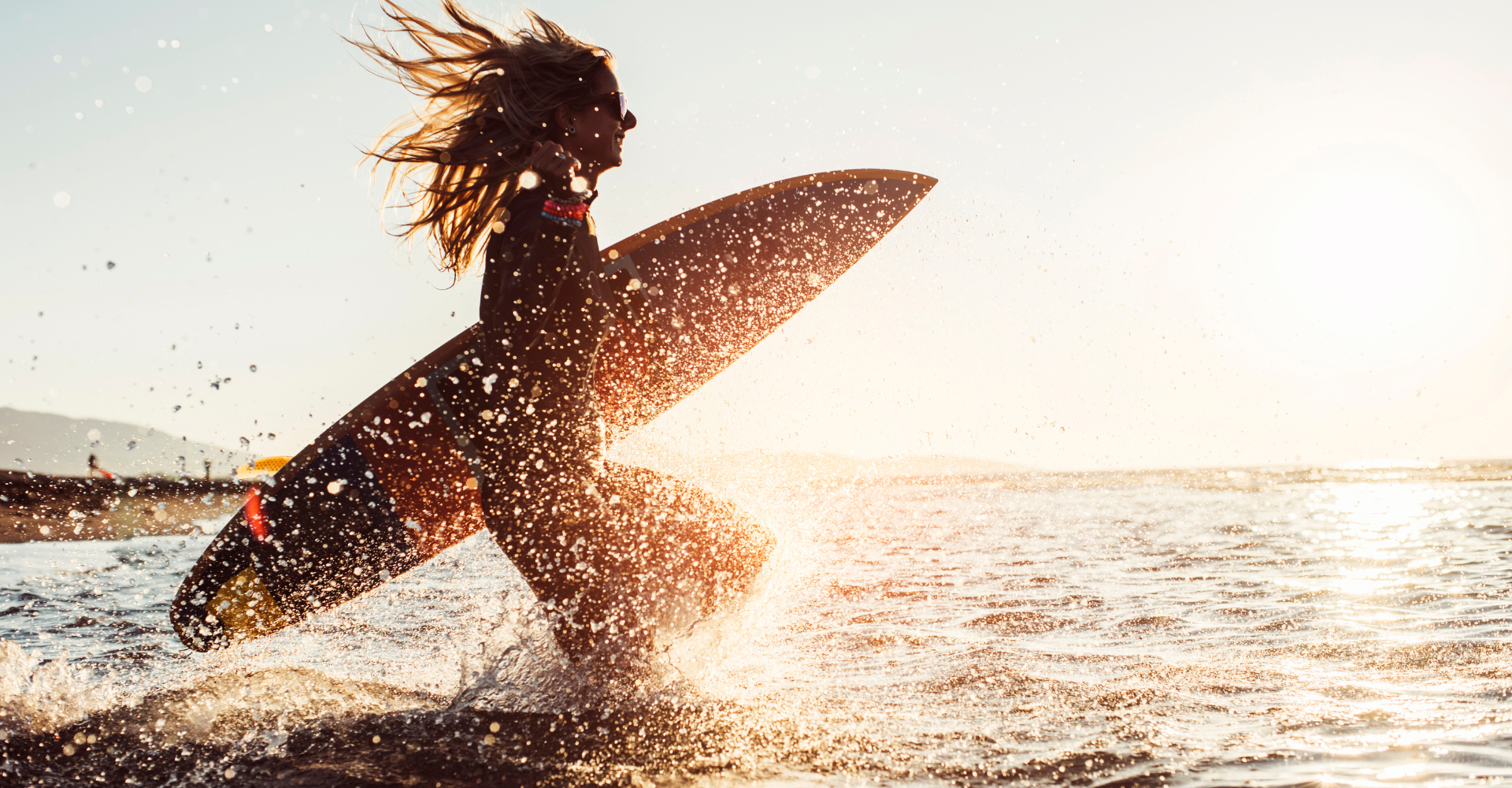 Woman running into the water surfing