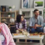 Woman sitting apart from a conversation